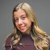 Smiling young woman with blonde wavy hair wearing a brown ribbed top