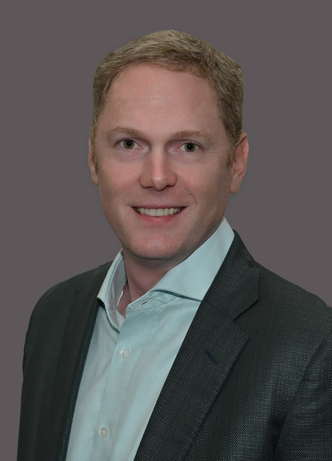 Smiling professional in dark blazer and light blue shirt