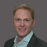 Smiling professional in dark blazer and light blue shirt