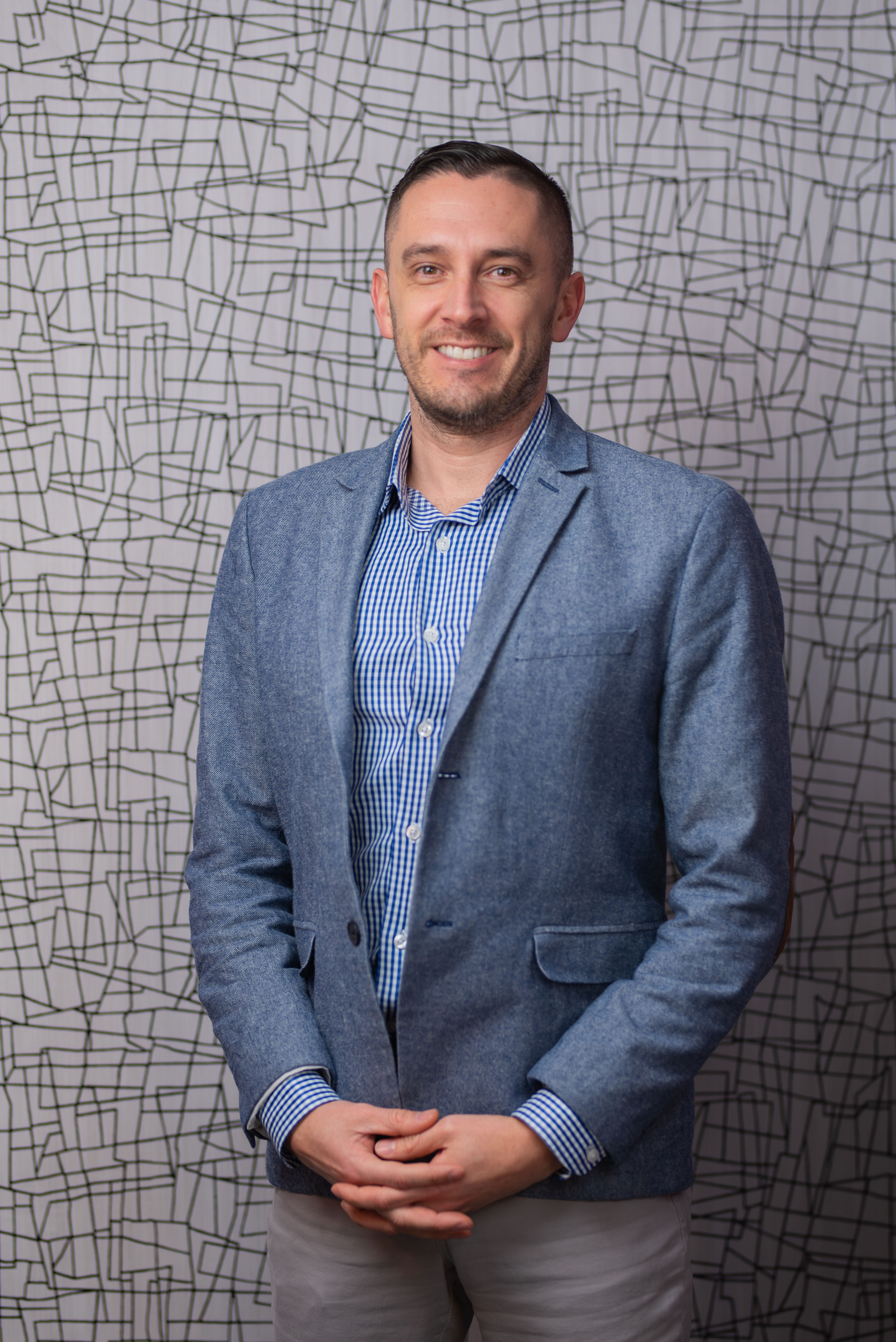 Professional man in blue blazer and checkered shirt, smiling