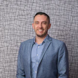 Professional man in blue blazer and checkered shirt, smiling