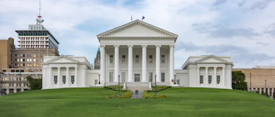 Virginia State Capitol building with white columns and neoclassical architecture on green lawn