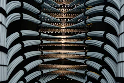 Network server rack with bundled white and black ethernet cables connected to illuminated patch panels in a data center