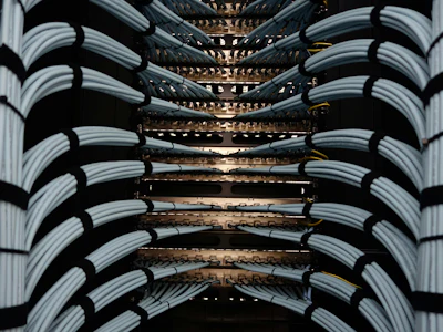 Network server rack with bundled white and black ethernet cables connected to illuminated patch panels in a data center