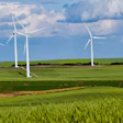 Wind turbines in green agricultural fields under blue sky with white clouds