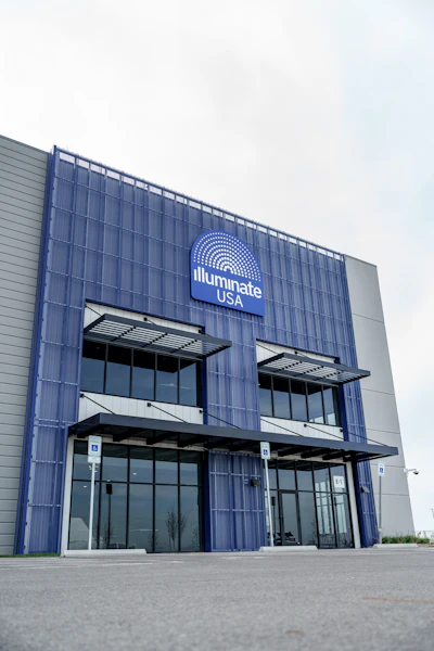 Illuminate USA corporate building entrance with blue corrugated metal facade and illuminated logo sign