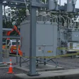 Industrial electrical substation with large transformers, safety barriers, and equipment under maintenance