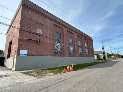 Red brick industrial building with gray base panel and street-level signage
